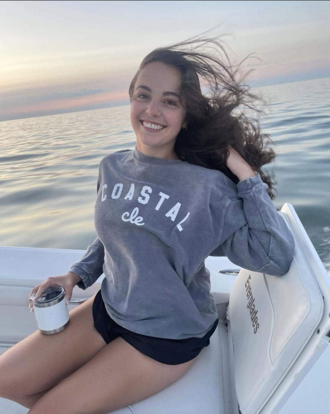 Hannah, WAKE founder, smiling on a boat on Lake Erie at sunset